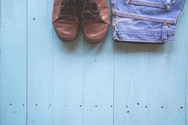 Pastellfarbe, Weinleseart, Schuhe, Jeans auf hölzernem Hintergrund