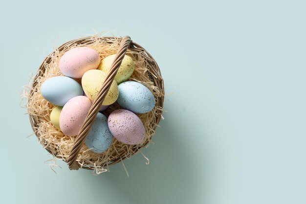 Pastellfarbene Ostereier im Weidenkorb für fröhliche Feiertage und Feiern auf blauem Hintergrund