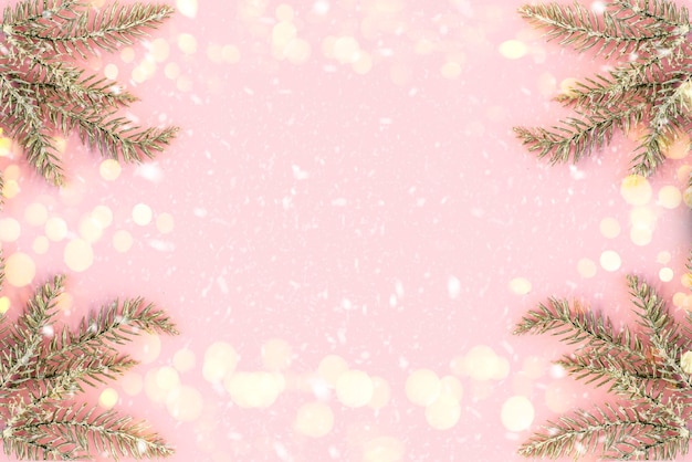 Foto pastellrosa hintergrund mit schneebedeckten tannenzweigen und kopienraum für text. weihnachten, festlicher oder winterlicher hintergrund. ansicht von oben, flach legen, mock-up