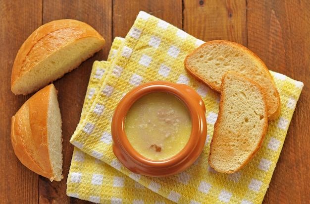 Pastete mit Butter in einem Keramiktopf und Toastbrot auf Textilserviette