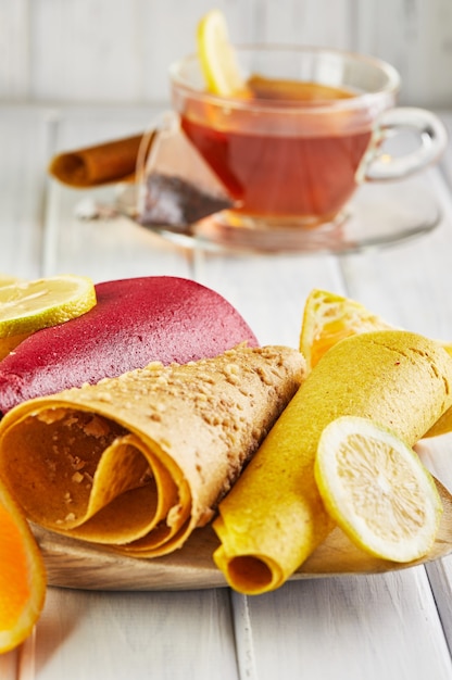 Pastilha doce de frutas puras em rolinhos com frutas cítricas e chá com limão. Doces saudáveis - pirulitos, chips de frutas.