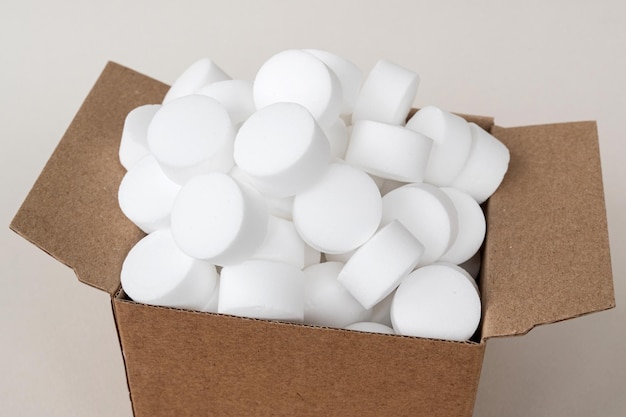 Pastilhas brancas redondas de sal para lava-louças em uma caixa Um conjunto de cápsulas brancas em uma caixa aberta