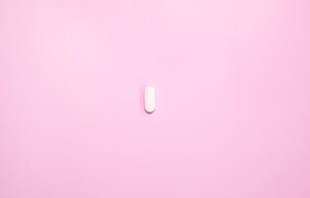 Una pastilla blanca sobre un fondo rosa.