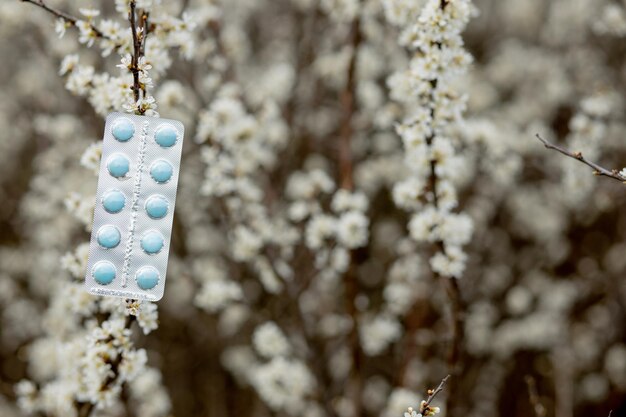 Pastillas para la alergia contra el fondo de las plantas florecientes.