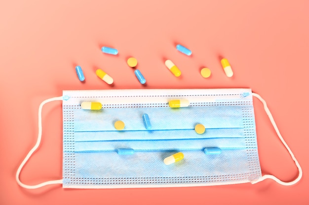 Pastillas amarillas y azules y una máscara médica sobre un fondo de melocotón