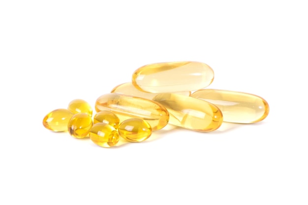 Pastillas amarillas de vitamina D se deslizan aisladas sobre fondo blanco Las vitaminas son antibióticos Omega 3