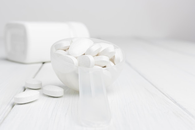 Pastillas blancas en una cuchara de plástico, tratamiento con medicamentos, vista de primer plano