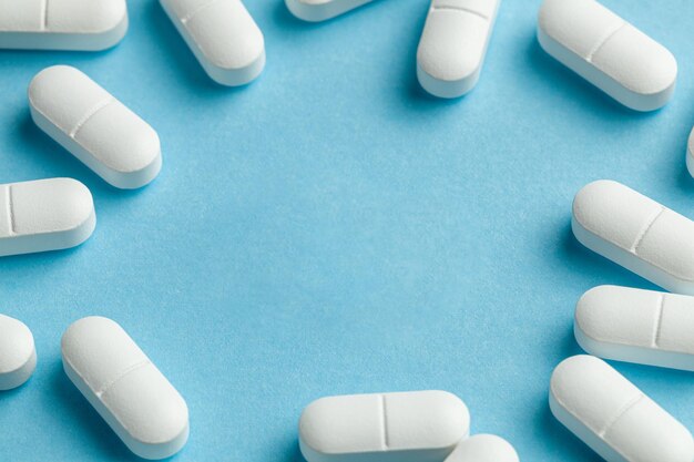 Pastillas blancas sobre fondo azul. Una tableta se rompe por la mitad, reduciendo la dosis del medicamento.