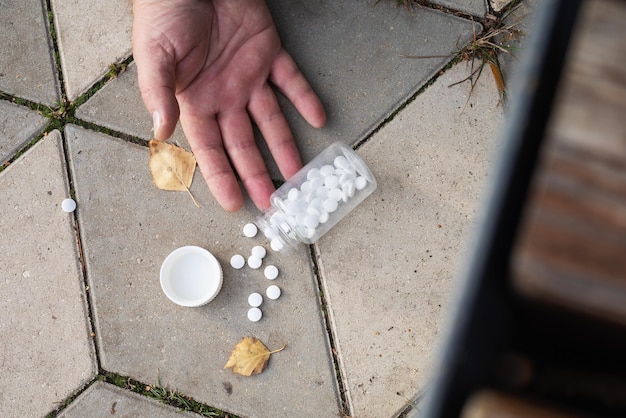 Las pastillas caen de las manos al suelo el concepto de un agudo deterioro de la salud en la calle