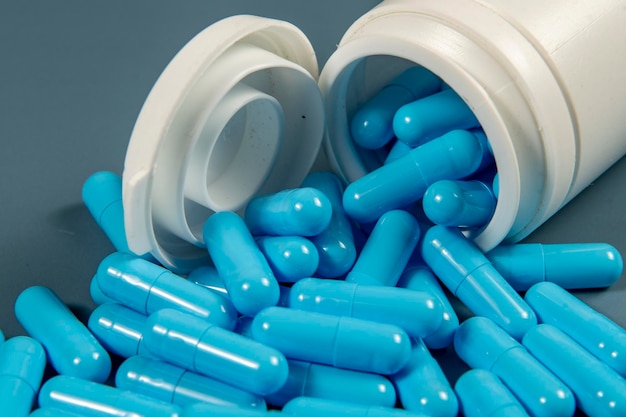 Pastillas de cápsulas antibióticas azules con textura con botella blanca Producción farmacéutica Salud mundial Resistencia a los antibióticos Pastillas en cápsulas de gelatina