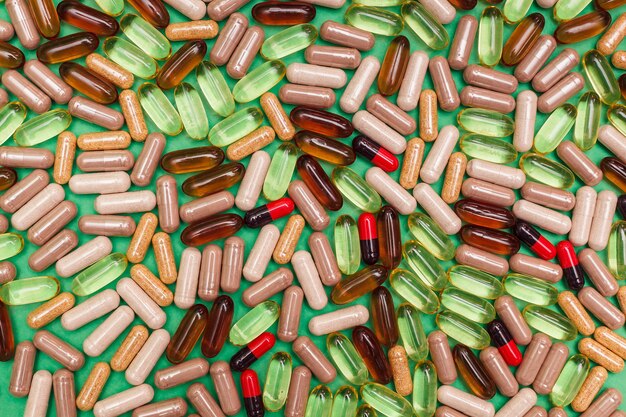 Pastillas y cápsulas multicolores sobre un fondo verde