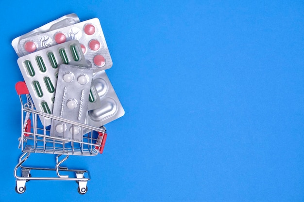 Pastillas en un carrito de compras sobre fondo azul.