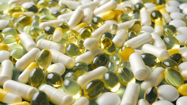 Las pastillas están esparcidas sobre la mesa. Tabletas en el fondo verde. Comprimidos medicinales, cápsulas.