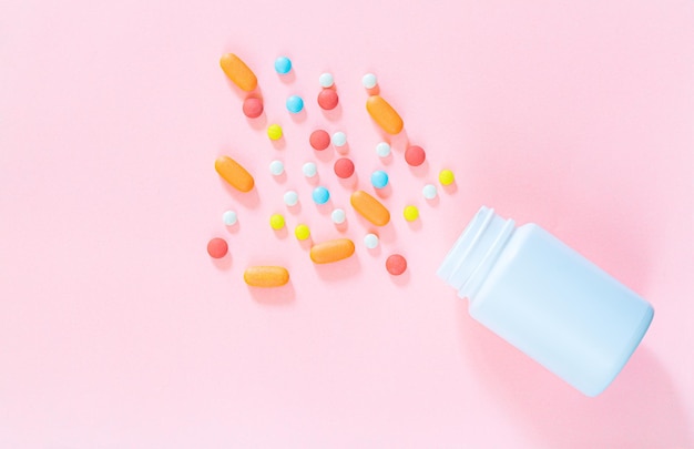 pastillas y frascos de pastillas con fondo rosa, pastillas blancas con enfoque selectivo y botella de vidrio marrón