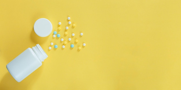 pastillas y frascos de pastillas sobre fondo amarillo y espacio de texto, Banner con pastillas esparcidas de una botella