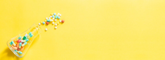 Pastillas y frascos de pastillas sobre fondo amarillo