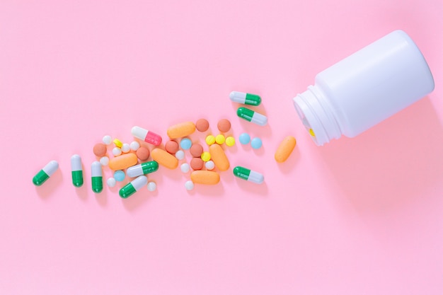 Pastillas y frascos de pastillas sobre fondo de color rosa