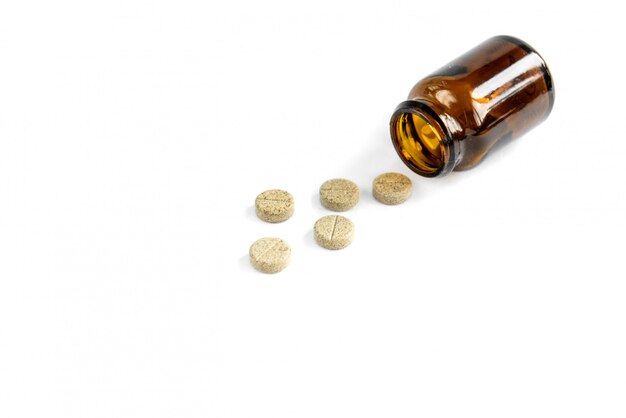 Pastillas de hierbas y frasco de vidrio aislado sobre fondo blanco.