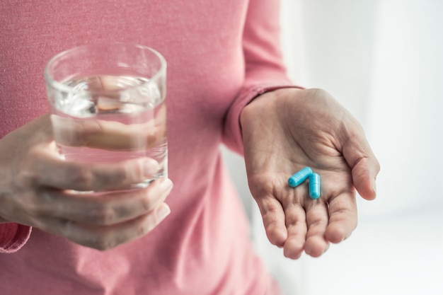 Pastillas en la mano de una mujer. Medicación en forma de cápsulas.