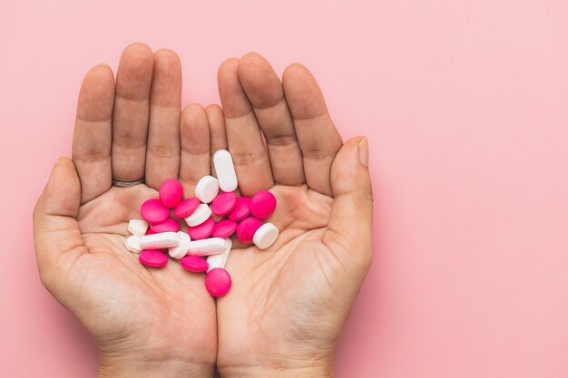 Foto con pastillas de medicina en la mano sobre un fondo rosa para el concepto médico y de atención médica