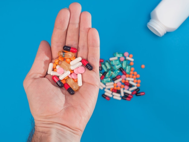 Pastillas multicolores en la mano sobre fondo azul.