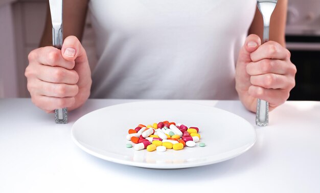 Pastillas multicolores en un plato blanco en la mesa Concepto de alimentos saludables Tomar suplementos de vitaminas