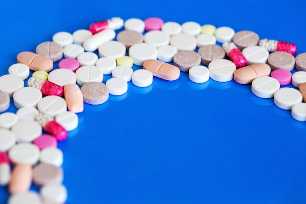 Pastillas multicolores sobre un fondo azul, medicina y salud