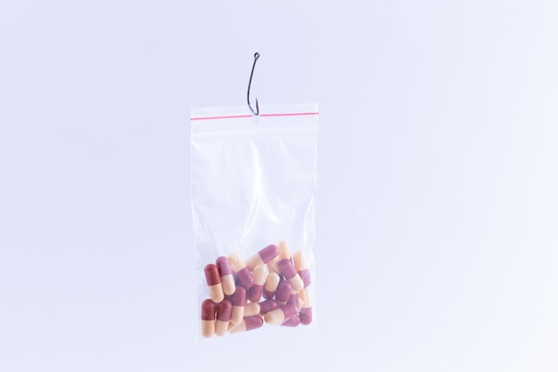 Pastillas o tabletas de colores que cuelgan en una pequeña bolsa ziplock en un anzuelo de pesca