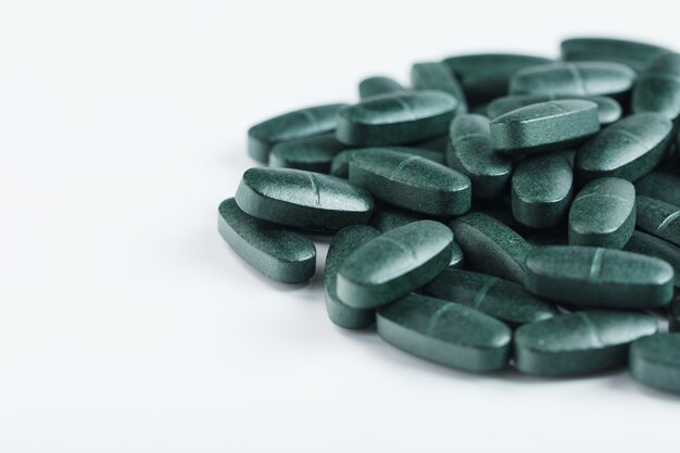 Pastillas con Vitaminas y Espirulina sobre un fondo blanco.