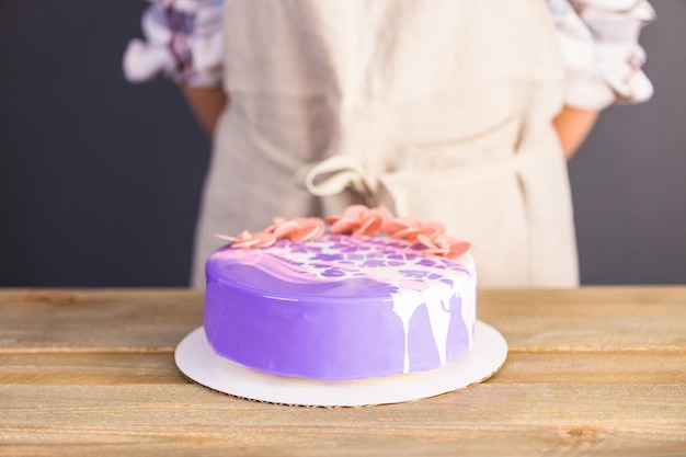 Pastre Shef macht Mousse-Kuchen mit lila Spiegelglasur und dekoriert mit schokoladenrosa Blüten.