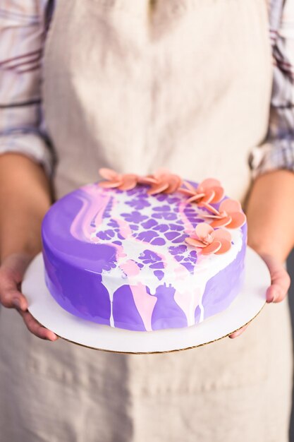 Pastre Shef macht Mousse-Kuchen mit lila Spiegelglasur und dekoriert mit schokoladenrosa Blüten.