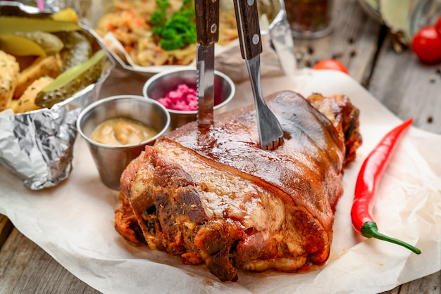 Pata de cerdo frita con papas sobre tabla de madera