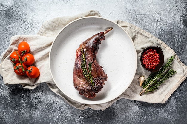 Pata de conejo al horno con hierbas, servida en servilleta textil.