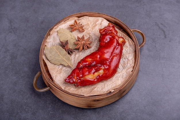 Las patas de cerdo rojo guisado están en un recipiente de bambú sobre un fondo oscuro