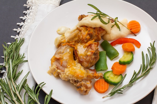 Patas de conejo al horno en vino blanco con salsa bechamel sobre plato de cerámica con verduras y romero. Carne dietética de conejo cocida al horno. Vista superior.