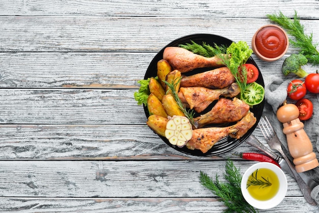 Foto patas de pollo al horno con patatas y verduras sobre un fondo blanco de madera carne vista superior espacio de copia libre