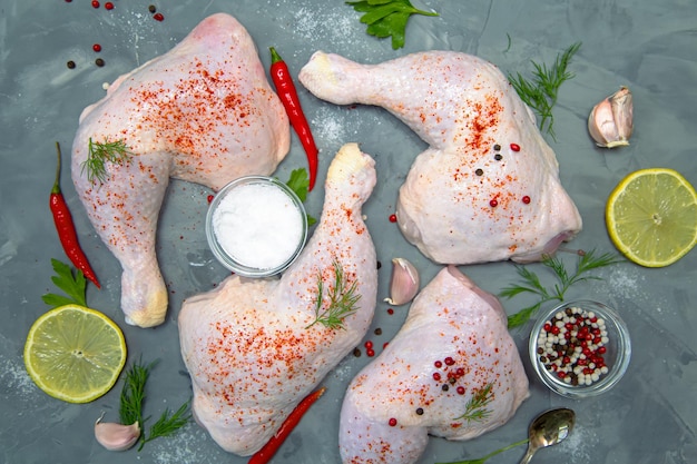 Patas de pollo crudas, ajo, chile, limón y hierbas sobre un fondo gris, vista superior