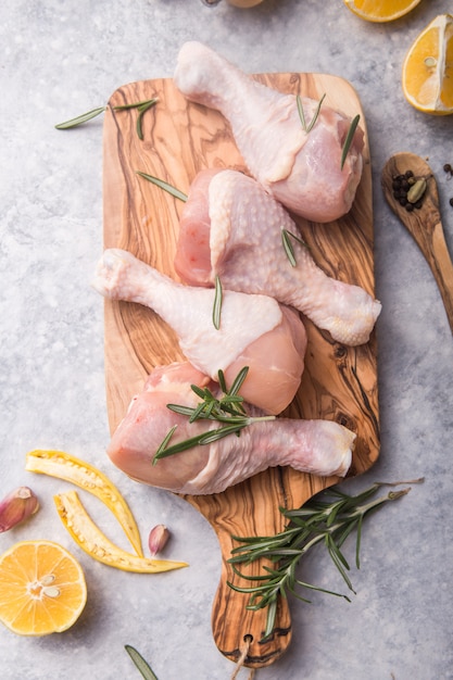 Patas de pollo crudas crudas sobre tabla de madera con hierbas para cocinar