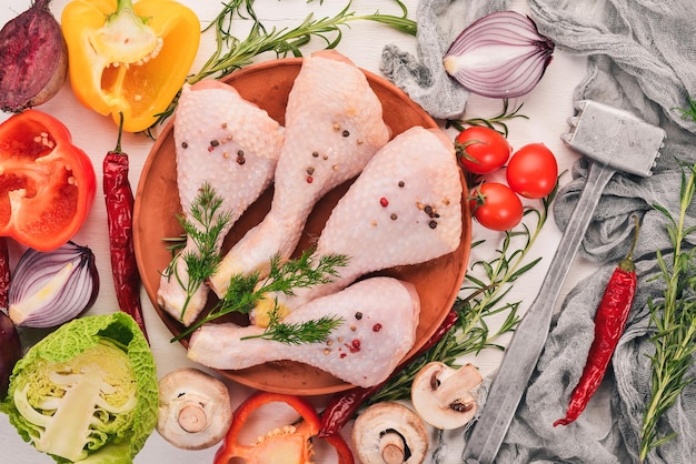 Patas de pollo crudas con verduras frescas y romero y especias sobre un fondo blanco de madera Vista superior Espacio libre para texto