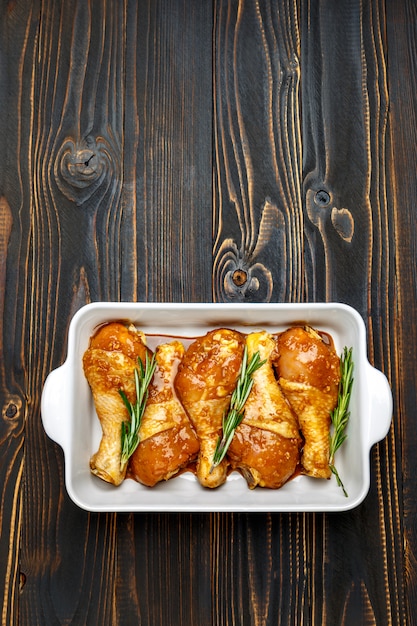 Patas de pollo crudo en una fuente para horno sobre una mesa de madera