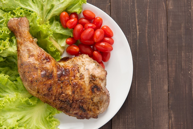 Patas de pollo a la parrilla y verduras en la mesa de madera.