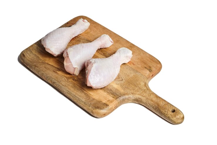 Patas de pollo con piel acostada sobre una tabla de cortar de madera Carne de aves aislada sobre fondo blanco