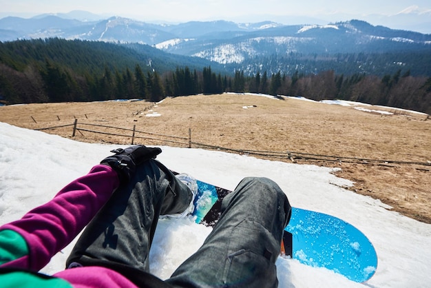 Patas de snowboarder y snowboard azul brillante en nieve blanca hermoso paisaje de fondo de invierno