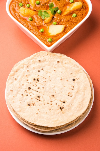 Patata al curry o aloo o Aaloo masala freír con guisantes, plato principal indio servido con pan plano también conocido como chapati o Roti, enfoque selectivo