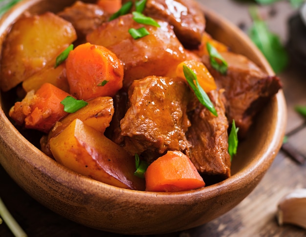 Patata al horno con carne Bourguignon en la vieja mesa de madera en estilo rústico