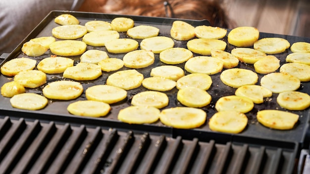 Patata cortada en círculos pequeños, sazonada con especias, asada a la parrilla eléctrica