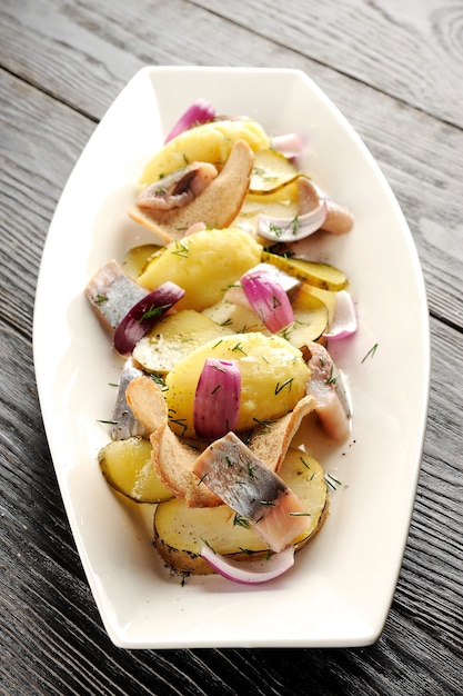 Patata frita y arenque en escabeche con cebolla y chips de pan