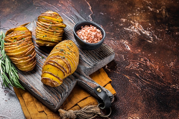 Patata Hasselback asada con tomillo fresco y romero Fondo oscuro Vista superior Espacio de copia