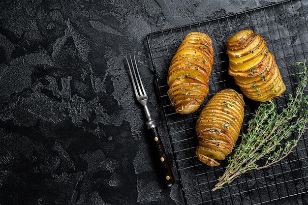 Patata Hasselback casera tradicional americana con hierbas frescas Fondo negro Vista superior Espacio de copia