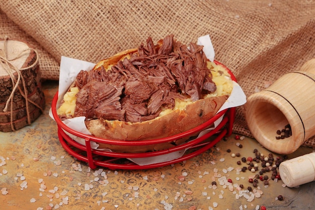 Patata kumpir al horno rellena con salchicha de queso, aceitunas, pimientos y maíz.